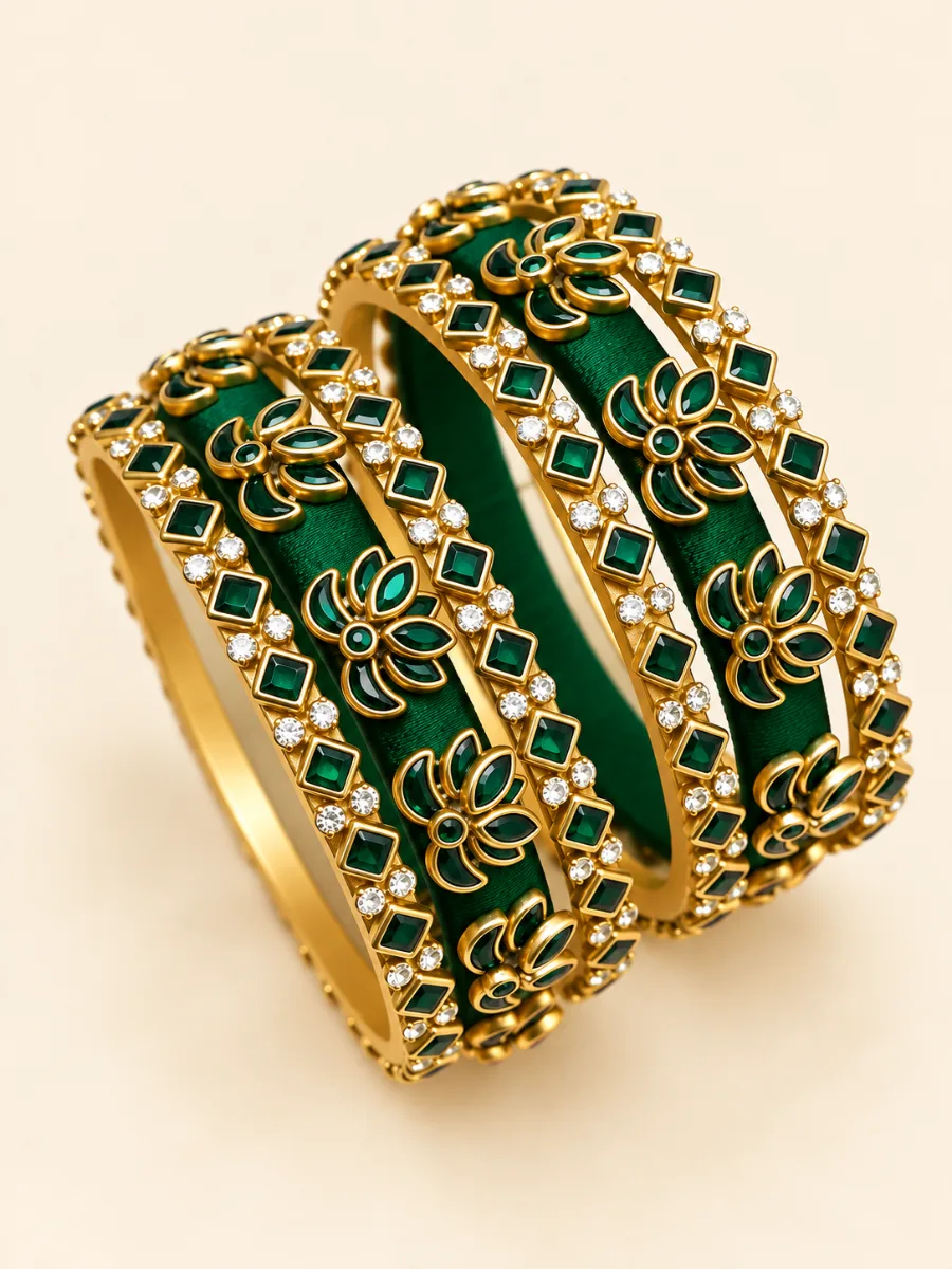 Emerald Green Kundan Floral Designer Bangles — Elegant emerald green thread-wrapped bangles featuring gold-toned floral motifs, green stone accents, and sparkling clear embellishments.