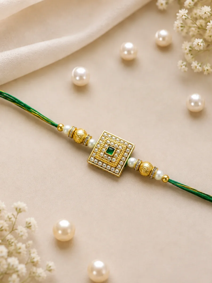 Rajmukut Rakhi — Green-thread Rakhi with a square central centerpiece and gold-tone and white decorative detailing.