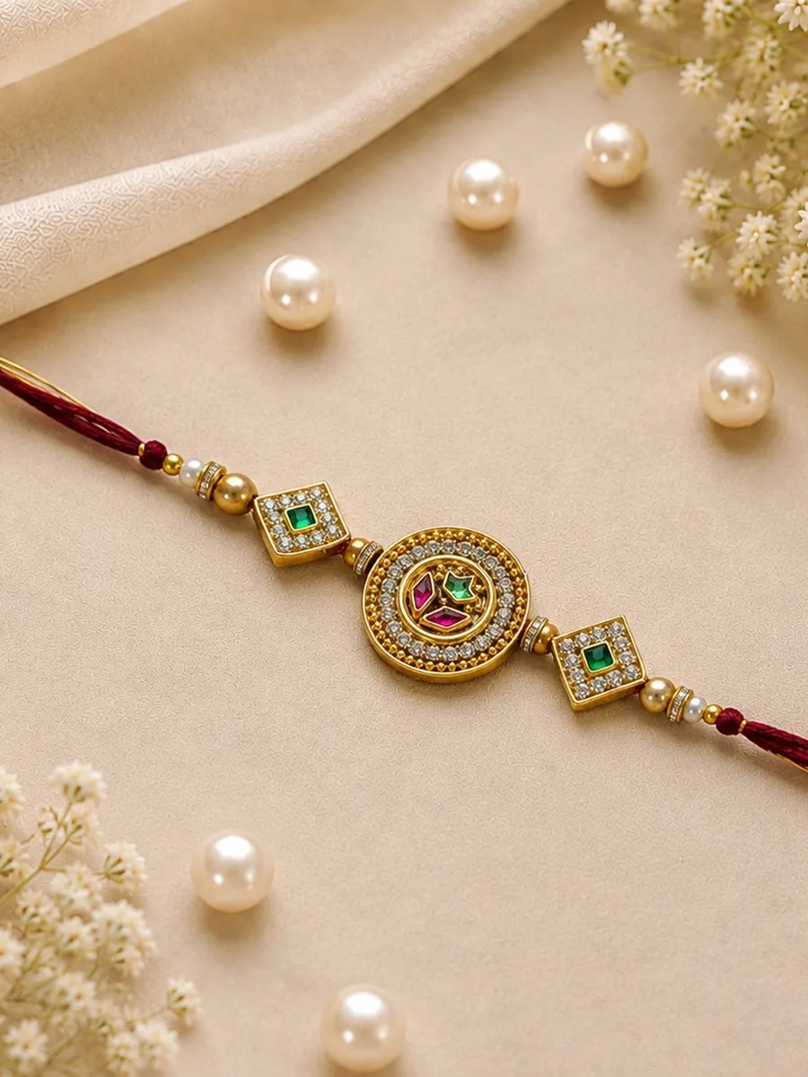 Rajtilak Rakhi — Rakhi with a red-maroon thread, circular centerpiece, green and gold-tone detailing, and square decorative side elements.